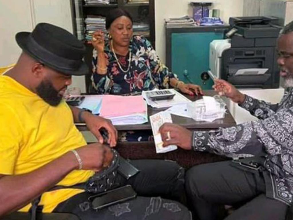Martin Bakole recevant des mains de la caissière du ministère des Sports la somme de 100 000$ (cent mille dollars américains) en liquide.