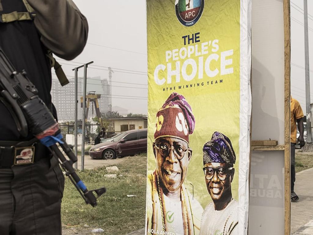 Un agent de sécurité devant une affiche électorale en faveur de Bola Tinubu, le leader du Congrès des progressistes (APC), le 18 février 2023, en amont des élections présidentielles prévus au Nigeria le 25 février. Private security stands next to an election poster for All Progressive Congress (APC) leader, Bola Tinubu in Lagos on February 18, 2023, ahead of the Nigerian presidential election scheduled for February 25, 2023. © JOHN WESSELS/AFP