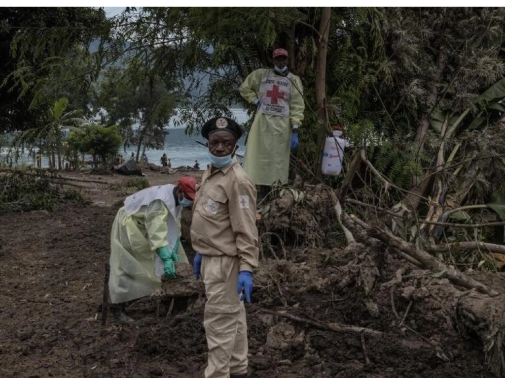 Des volontaires de la croix-Rouge tentent de récupérer un corps coincé dans la boue le 8 mai 2023 à Bushushu. AFP - G